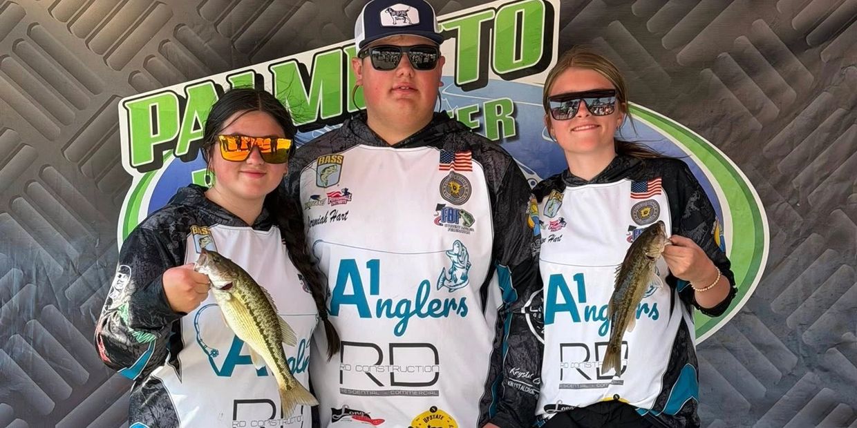 Three anglers proudly hold their catches at a fishing tournament.