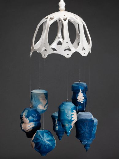 Blue and white ceramic wind chime with intricate designs hanging from a white ceramic dome.