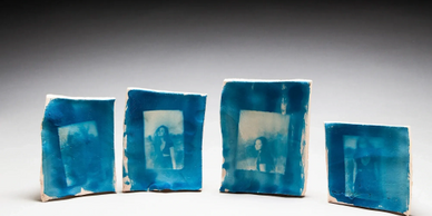 Four blue cyanotype photo tiles on a gray surface.