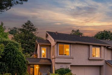 A cozy house at sunset with warm lights glowing inside.