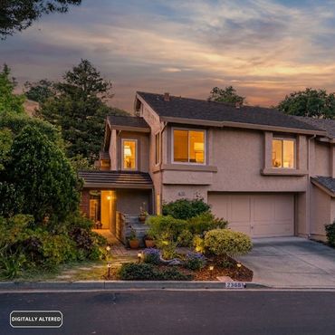A cozy house at sunset with warm lights glowing inside.
