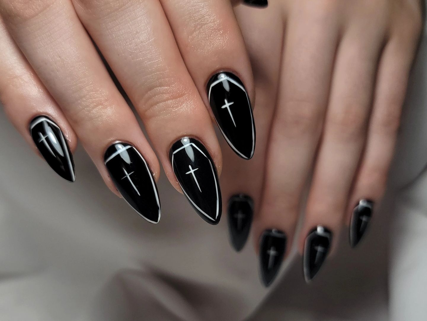 Black coffin-shaped nails with white cross and outline designs.