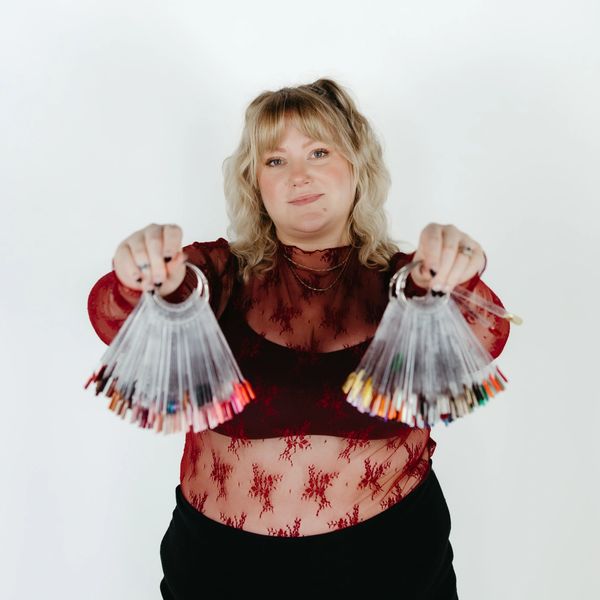 Woman presenting two fans of colorful nail polish samples.