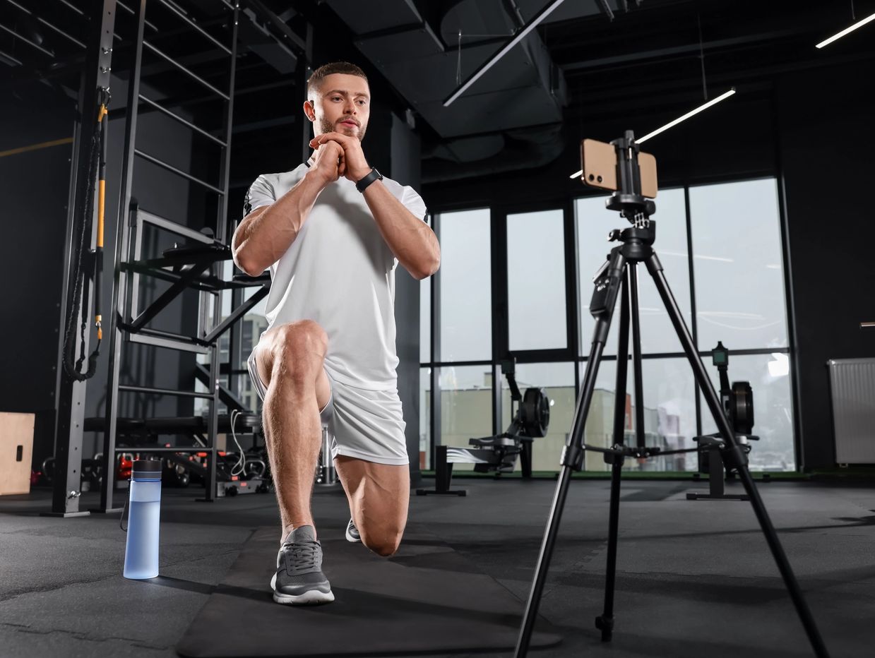 A male person is doing lunge exercise on video call through mobile phone.