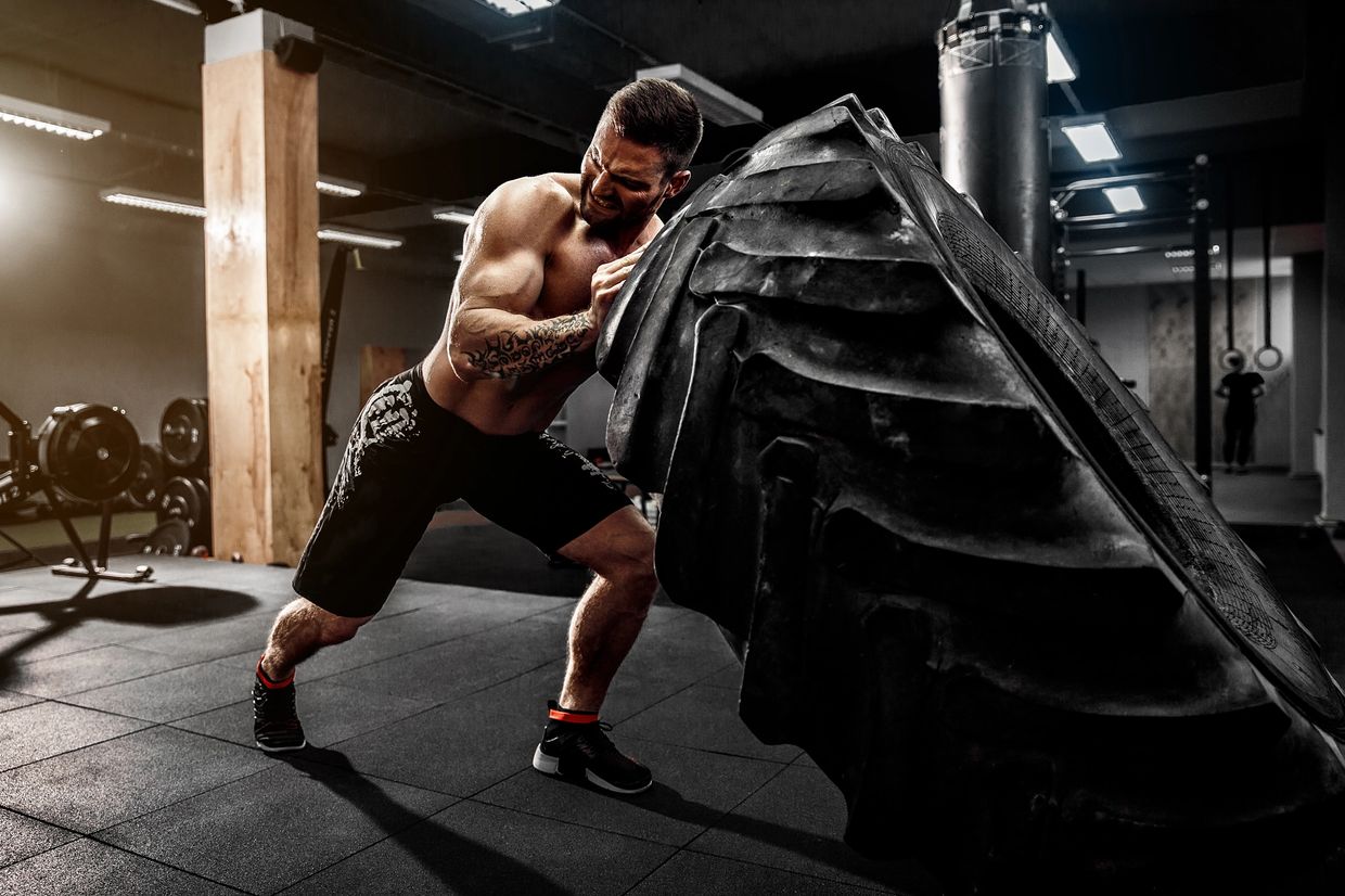 A male athlete is doing tyre flip workout.