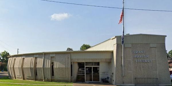 The Grant Parish Library building with two flagpoles and a clear blue sky.