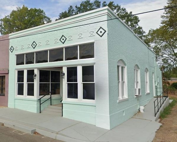 A mint green brick building with black diamond decorations and large windows.