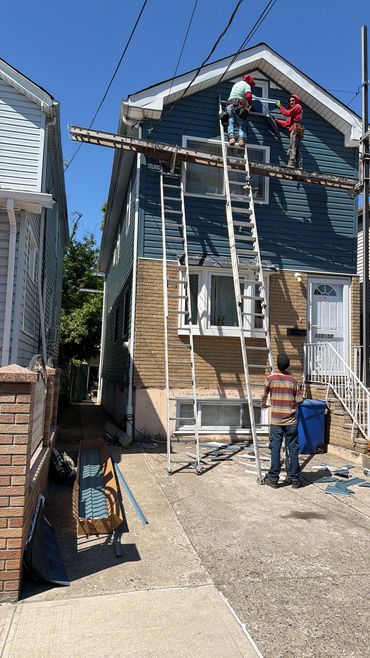 Two workers on scaffolding fixing a blue house panel.