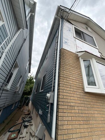 Two houses with siding construction and cluttered alley.