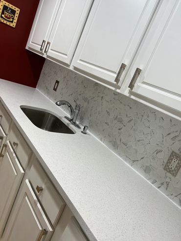 White kitchen counter with sink and cabinets.