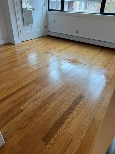 Empty room with polished wooden floors and large window.