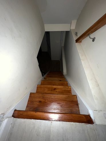 Narrow wooden staircase in a dimly lit space.
