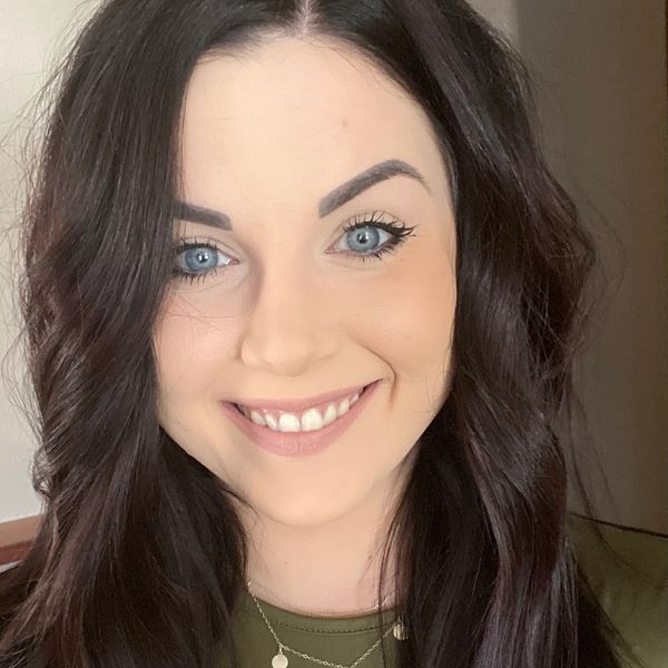 Rebecca Feather standing in front of a green background smiling