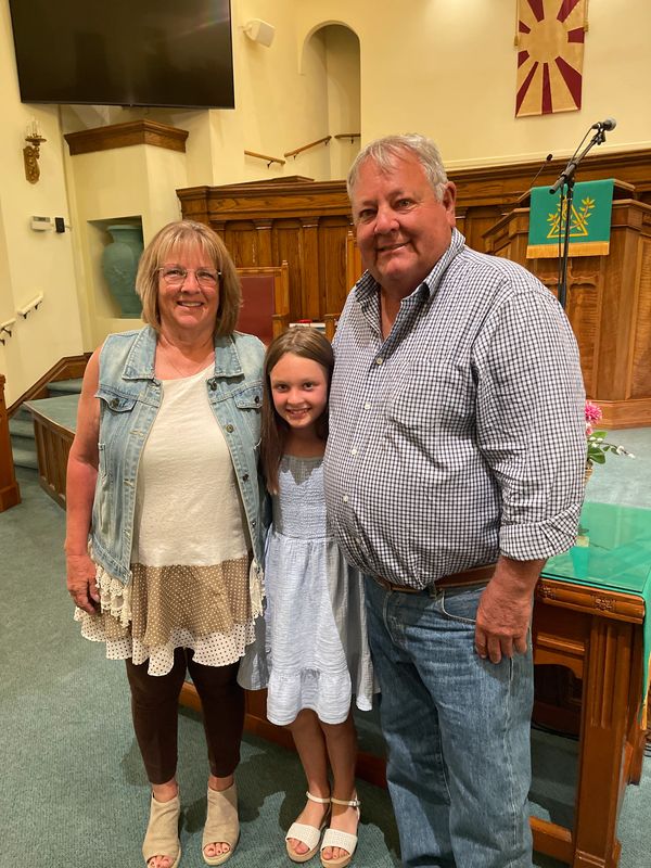 Smiling family of three posing in a church.