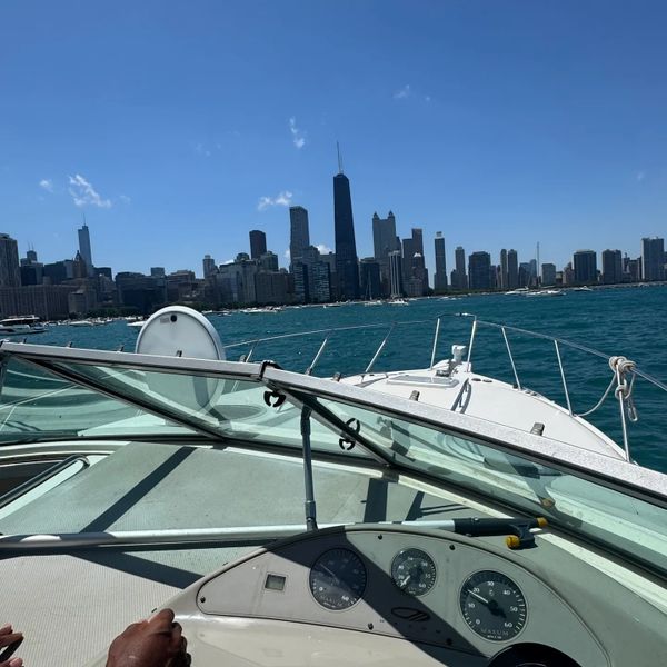 View of a city skyline from a boat on clear blue water under a sunny sky.