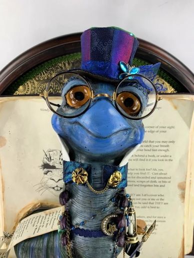 Artwork, sculpted blue bookworm, smiling, wearing a top hat