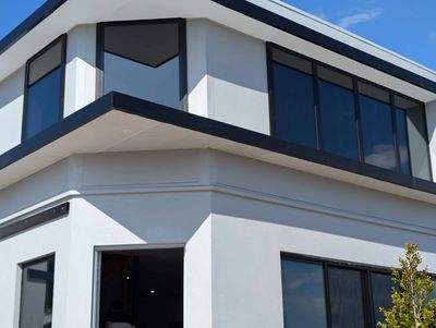 Modern white building with large windows and a clear blue sky.
