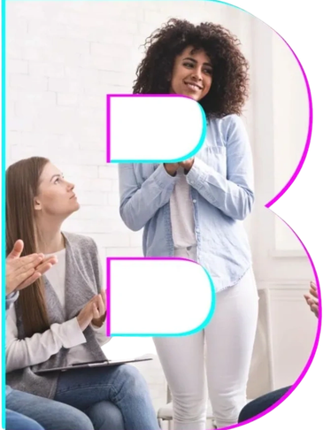 A woman stands smiling while others applaud in a supportive group setting.