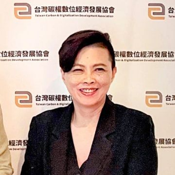 A woman smiling in front of a Taiwan Carbon &amp; Digitalization Development Association backdrop.