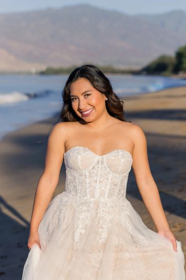 Smiling woman in a white strapless dress on the beach.