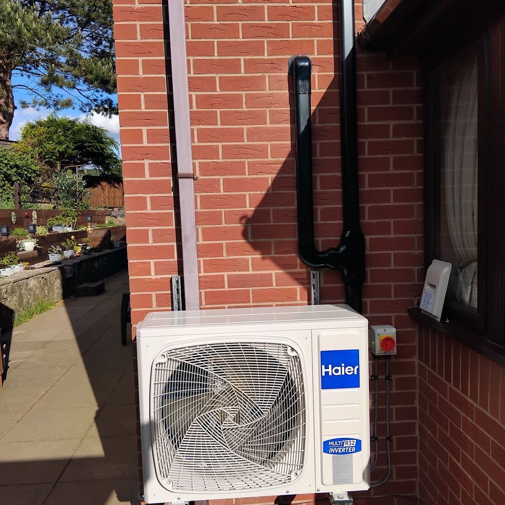 Haier outdoor air conditioning unit mounted on a brick wall.