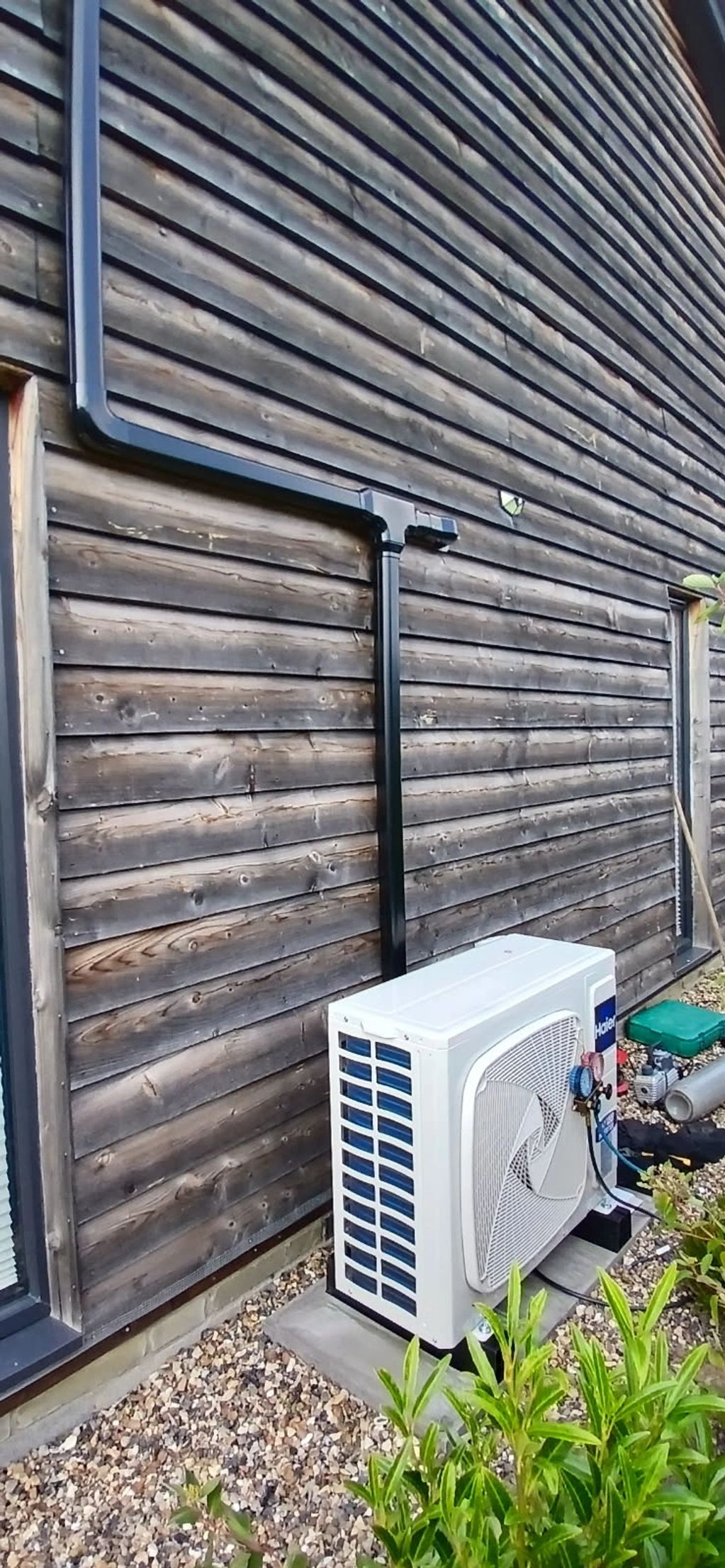 Outdoor air conditioning unit installed beside a wooden house wall.