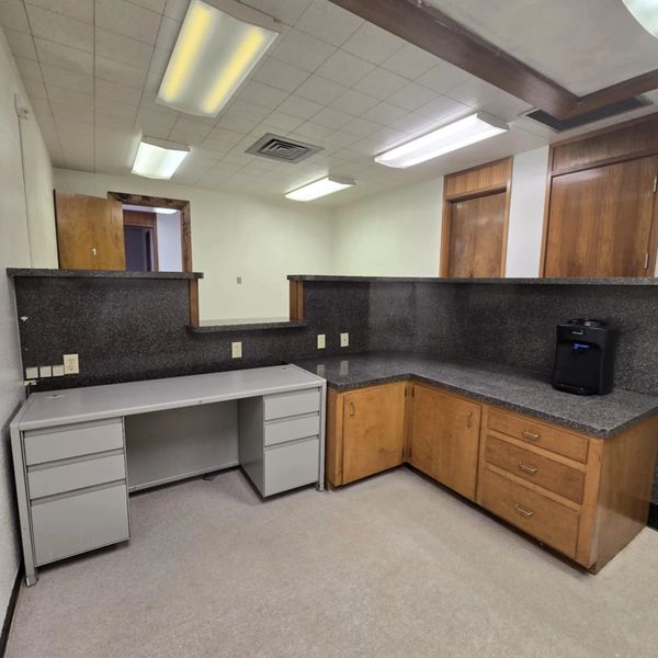 Empty office reception area with granite countertops and wooden cabinets.
