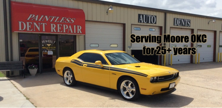 Yellow Dodge Challenger in front of a paintless dent repair shop with service info.