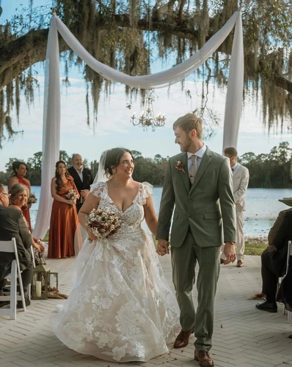 Bride and groom walking down the aisle outdoors at The Barn at Crescent Lake, surrounded by guests a