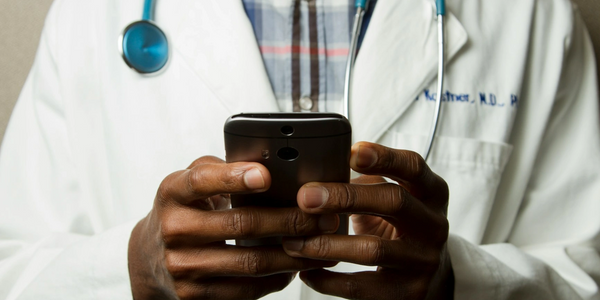 Elderly woman showing a blood pressure monitor during a video call at home.