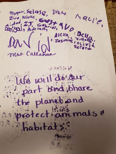 Handwritten note pledging to protect animals and habitats, signed by multiple people.