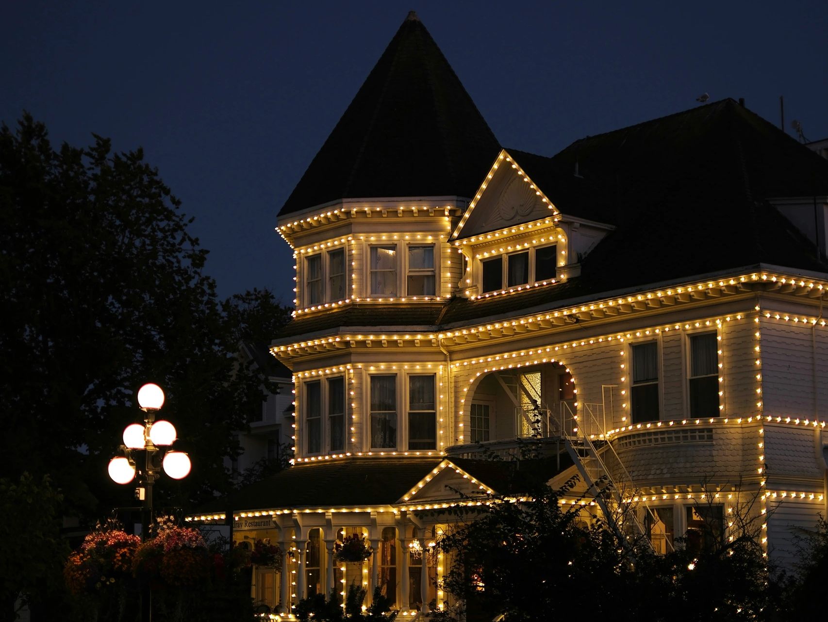 A Victorian house adorned with warm string lights at night.