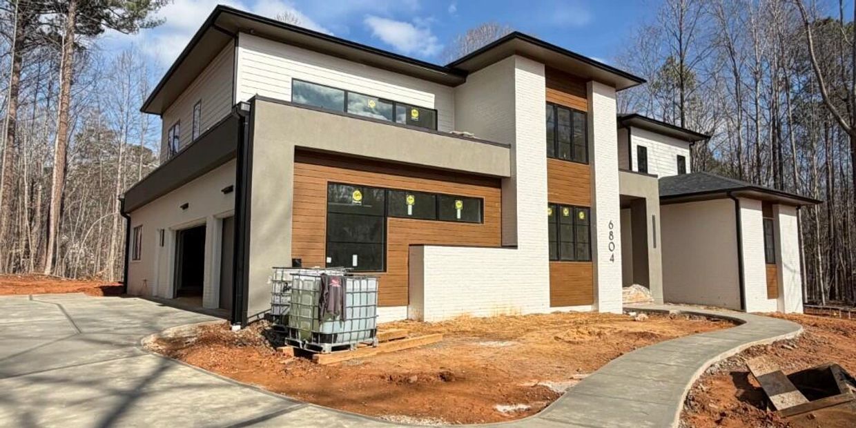 Modern two-story house under construction with a curved concrete walkway.