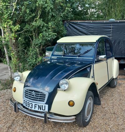 Classic two-tone Citroën 2CV parked outdoors.