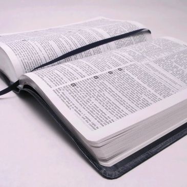 Open book with a black bookmark on white surface.