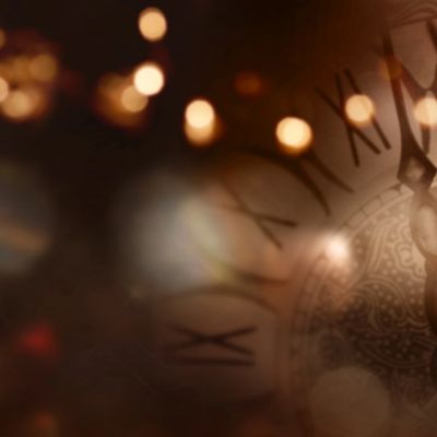 Close-up of an antique clock face with glowing bokeh lights.
