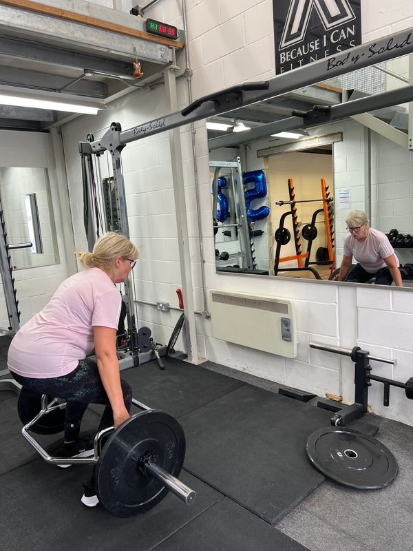 Older female over 60 years old lifting weights and deadlifting as resistance training in a female on