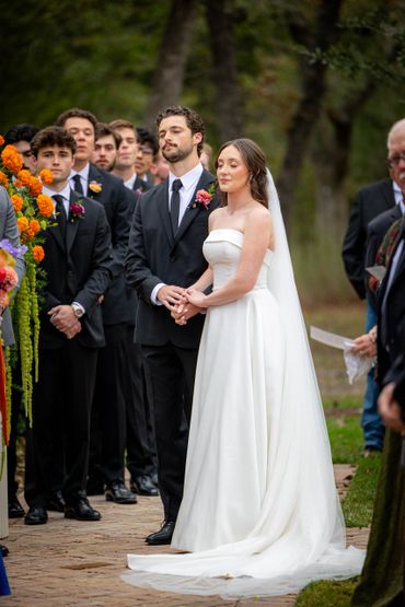 Bride and groom holding hands during outdoor wedding ceremony.
