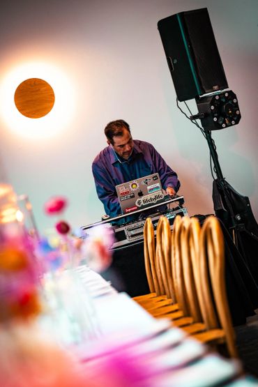 DJ performing at an event with a laptop and sound equipment.