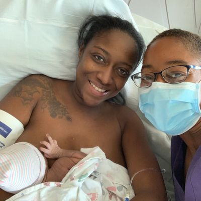 Mother pictured with her doula and newborn.