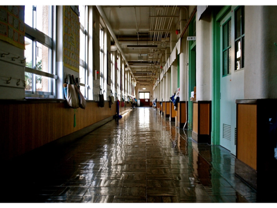 Empty, shiny school hallway with lockers and windows.