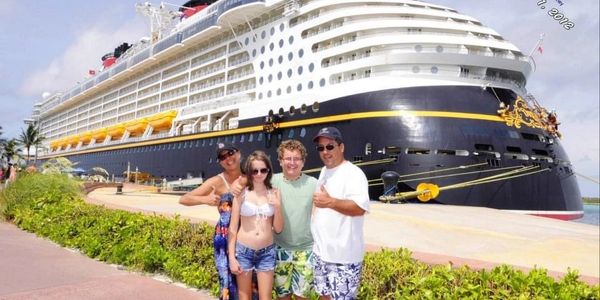 Family of 4 in front of Disney Dream cruise ship at Castaway Cay Disney's original private island