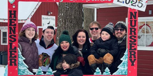 A group of people smiling in a festive holiday frame outdoors.