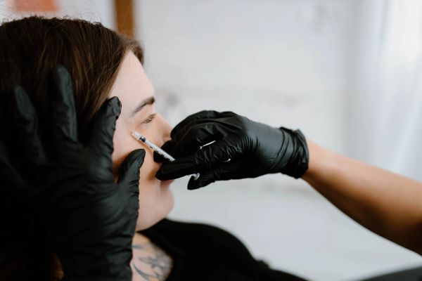 Person receiving a facial injection from a gloved professional.