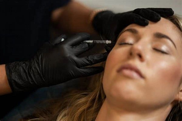A woman receiving a cosmetic injection near her eye.
