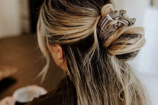 Woman with blonde hair styled in a messy bun using a plaid scrunchie.