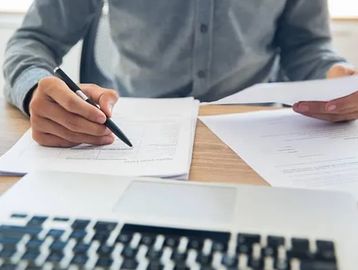 Close-up of person reviewing electrical service documents and contracts at a desk