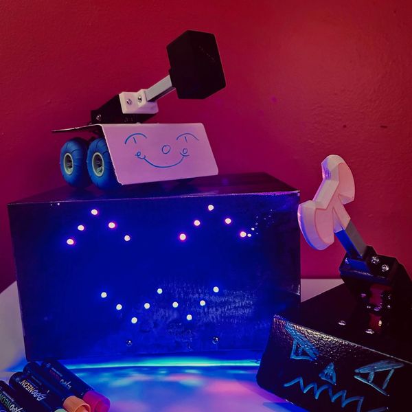 Two small robot-like models with faces, illuminated by blue and red light.