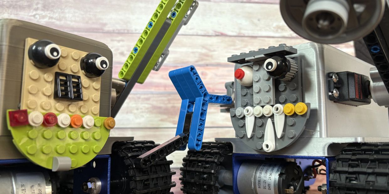 Two colorful LEGO robot faces with expressive eyes and teeth on tracked bases.