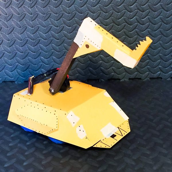 A small yellow robotic claw on a textured surface.